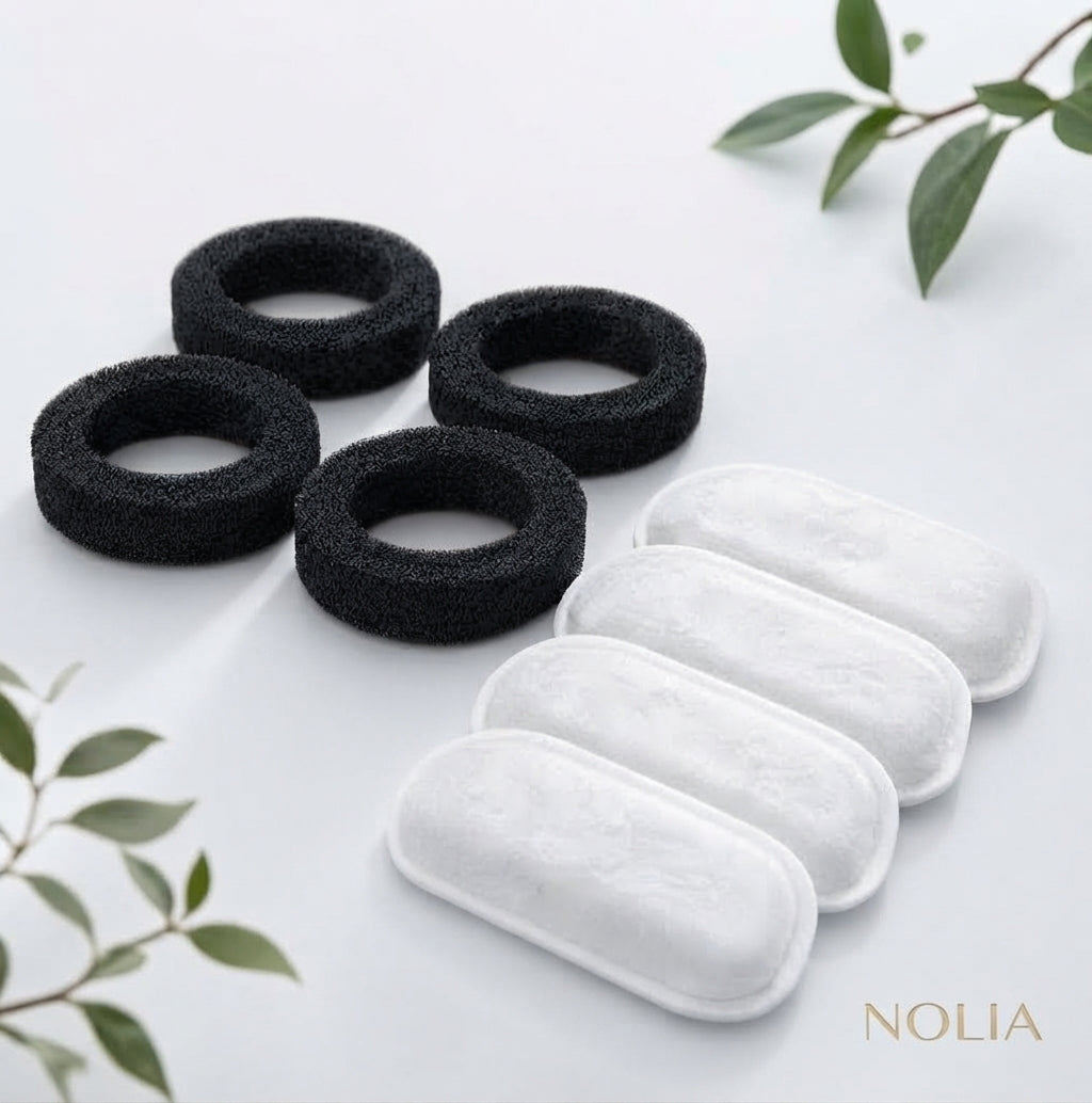 Lot de recharges pour fontaine à eau Nolia comprenant quatre filtres en mousse noire de pré-filtration et quatre filtres blancs haute pureté, présentés sur un fond épuré avec des touches de feuillage.